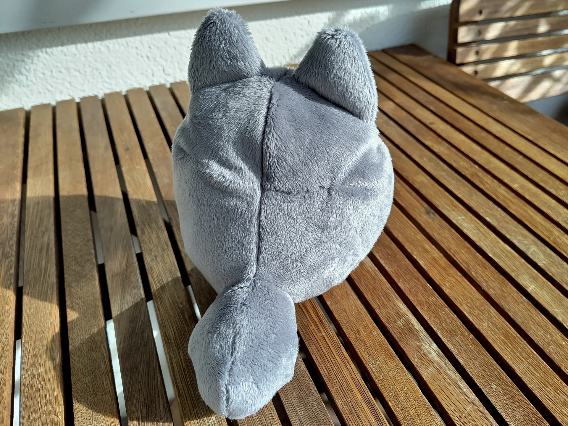 Totoro plushie seen from the back, it's all grey colored from there.