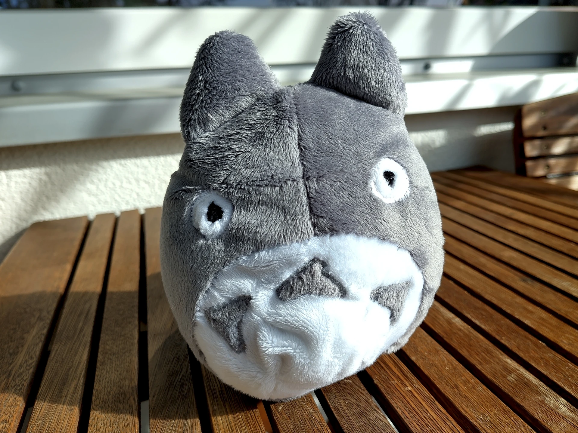 A very round grey and white plushie in the form of Totoro from the same named movie. White chest, grey triangular markings and gray ears.